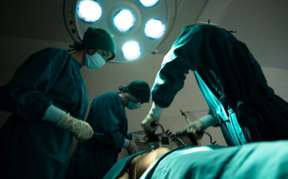 professional surgery team in the operating room, urgent surgery. Professional smart intelligent surgeons standing near the patient and performing an operation while saving his life Cateterismo